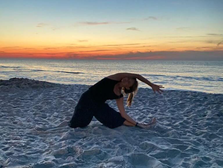 kobieta ćwicząca jogę nad morzem o zachodzie słońca