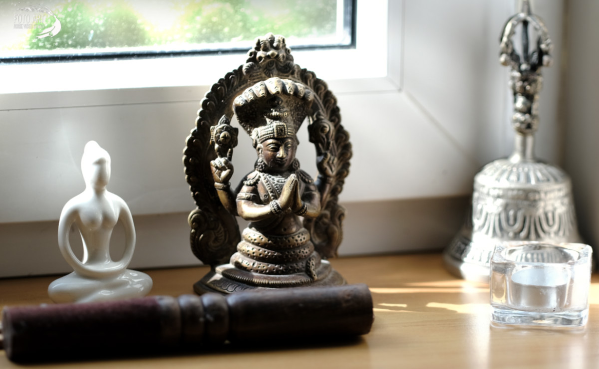 Patanjali figurka stojąca na parapecie w otoczeniu innych figurek, jasno oświetlona.