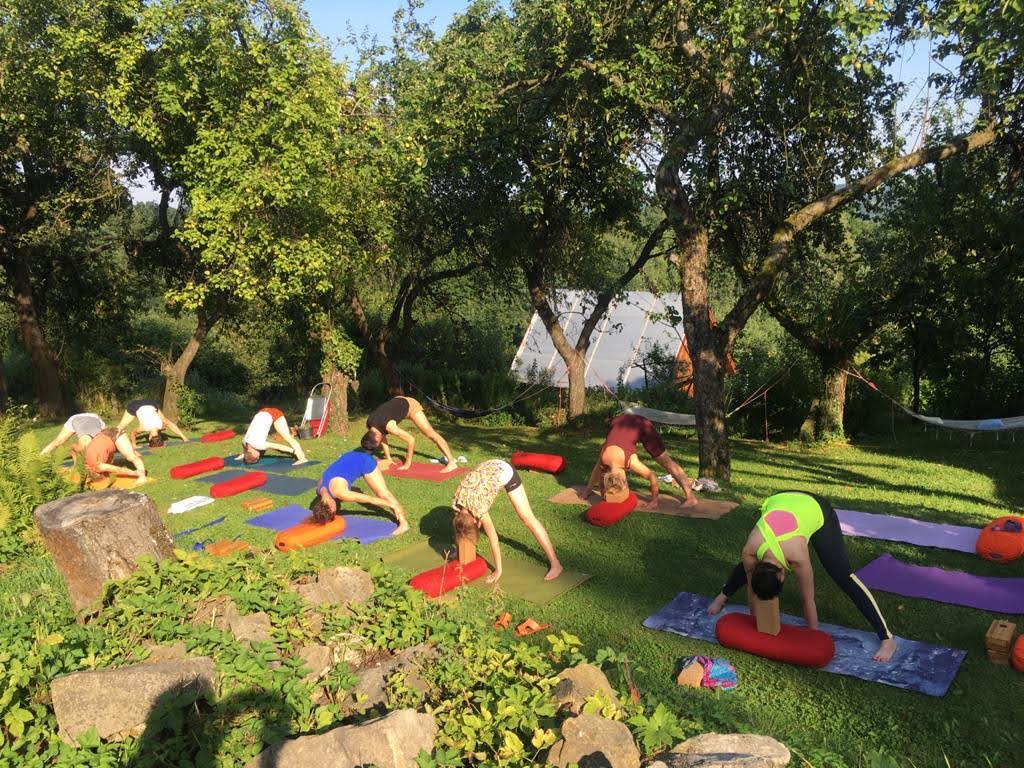 osoby praktykujące jogę w sadzie w górach w promieniach popołudniowego słońca 